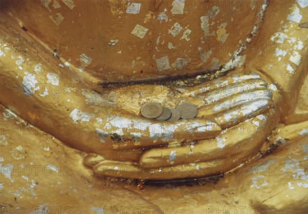 Donations for the temple in the hands of a Buddha sculpture. Buddha, Buddhism, religion, Bangkok,