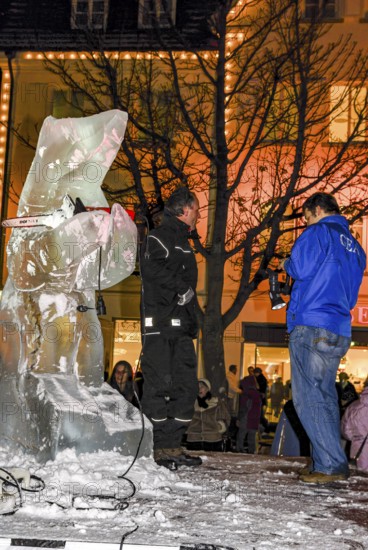 Ice carving artist in front of his ice sculpture interviewed by a GEA reporter during ice carving