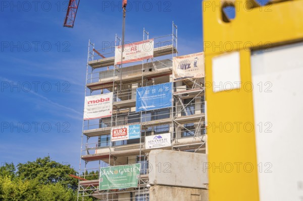 Multi-storey scaffolding structure with company logos on a sunny construction site, carpentry, new