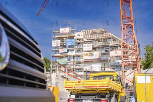 Construction site with crane and yellow construction vehicle in front of a building under
