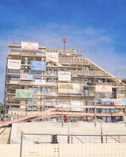 Large building under construction with scaffolding and various advertising banners as well as