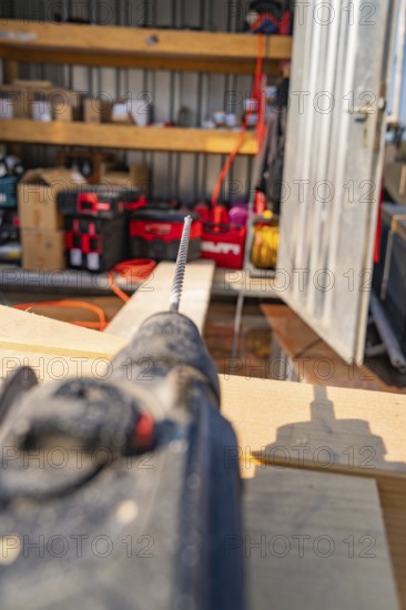 Close-up of a drill in a workshop environment with shelves and order, carpentry, new building,
