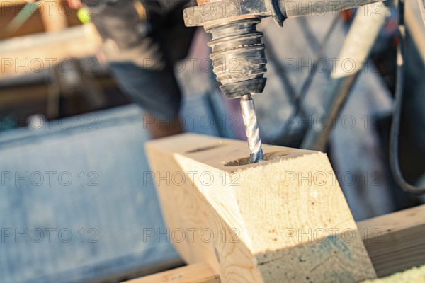 Detailed view of a drill drilling a hole in wood on a construction site, carpentry, new building,