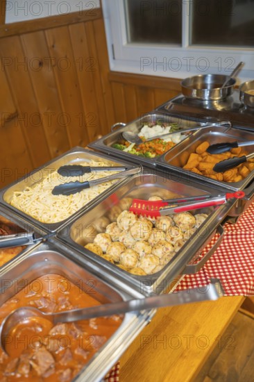 Buffet with various dishes and serving tongs on a table