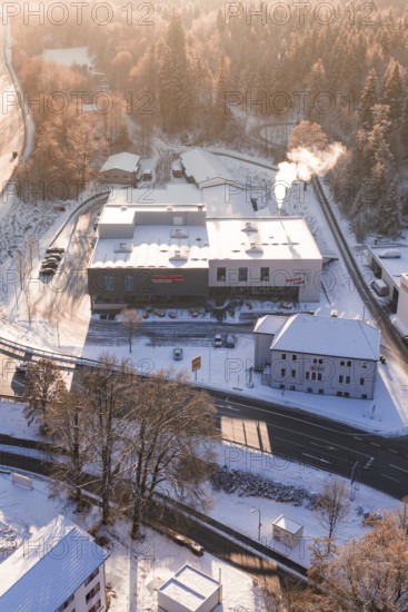 Snowy factory near a forest at sunrise, steam from chimney, Nagold, Calw district, Black Forest,