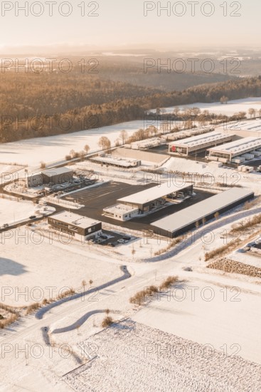 Snowy industrial landscape at sunset surrounded by fields and trees, Nagold, Calw district, Black
