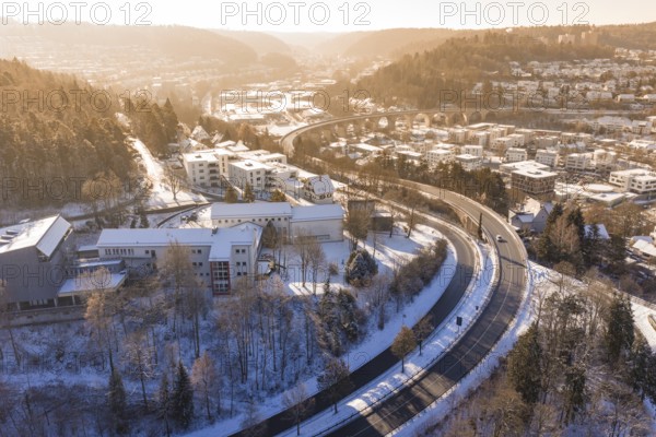 Snowy city landscape with a bridge and roads surrounded by hills and trees, Nagold, Calw district,