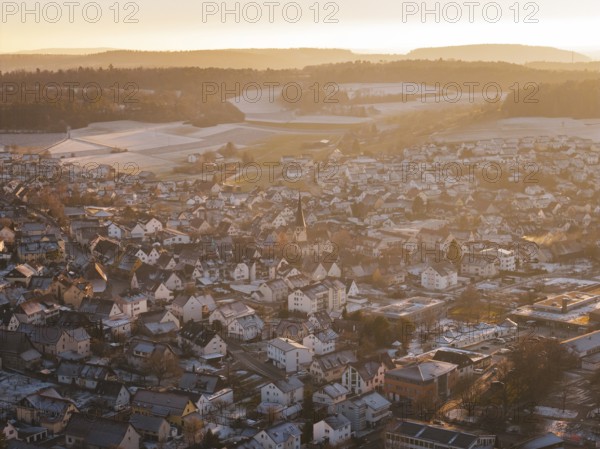 City view in golden light, snowy roofs and wintry hills in the background, Althengstett, Calw