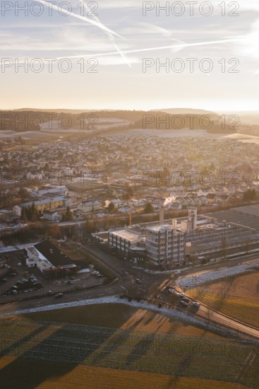 Urban panorama at sunset, pastel colors in the sky, surrounded by fields and snow-covered areas,