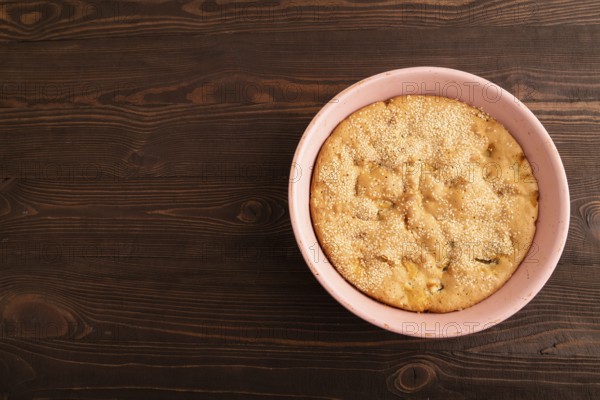 Apple Charlotte cake in baking dish on brown wooden background, top view, flat lay, copy space