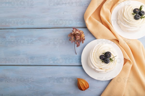 Pavlova Meringue dessert with crisp meringue and blueberry on blue wooden background with orange