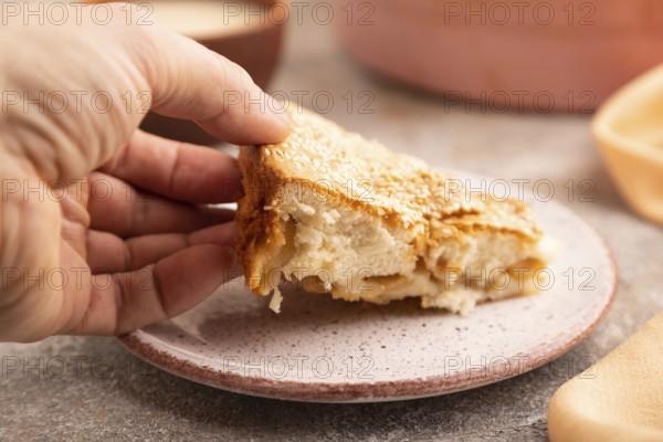 Apple Charlotte cake with hand on brown concrete background and orange linen textile, cup of milk,