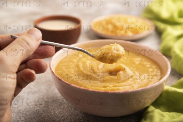 Pea cream soup, Puree, porridge in ceramic bowl with hand on brown concrete background and green