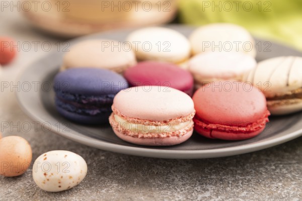 Macarons colourful cookies dessert, cup of coffee, on brown concrete background with green linen