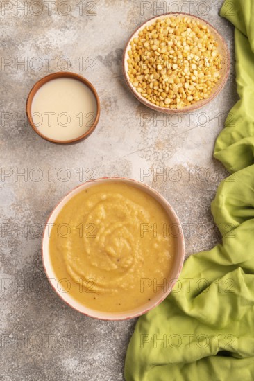 Pea cream soup, Puree, porridge in ceramic bowl on brown concrete background and green linen