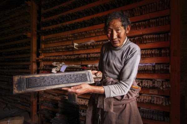 A Tibetan shows the printing block for sacred religious texts at the historic Tibetan Buddhist