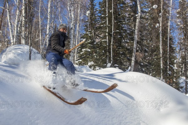 Skier with long traditional wooden skis and a long pole in the Altai Mountains, possibly the