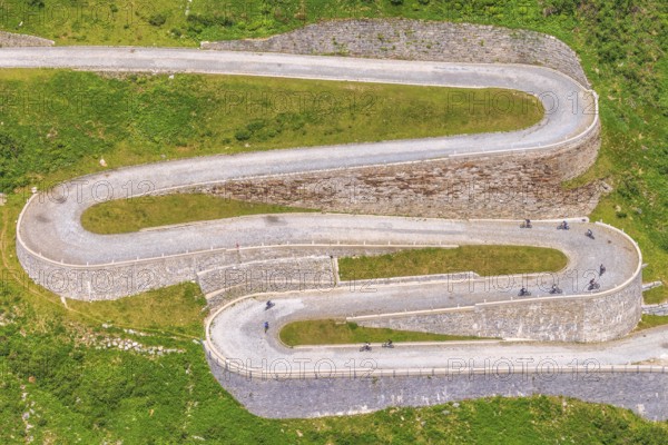 On a summer day, tourists cycle along the winding curves of Tremola Pass, Gotthard Massif, Ticino