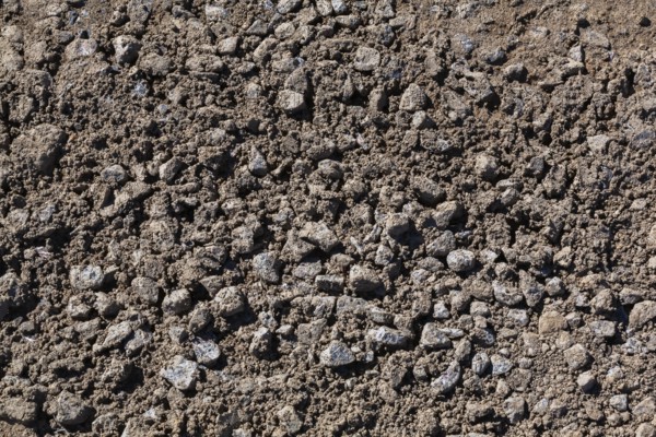 Close-up of sand mixed with grey crushed stone aggregate used to form a bed for constructing roads