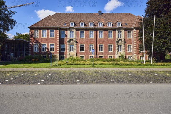 Town hall, brick buildings, flagpoles, façade with windows, dormers, parking boxes, sidewalk,