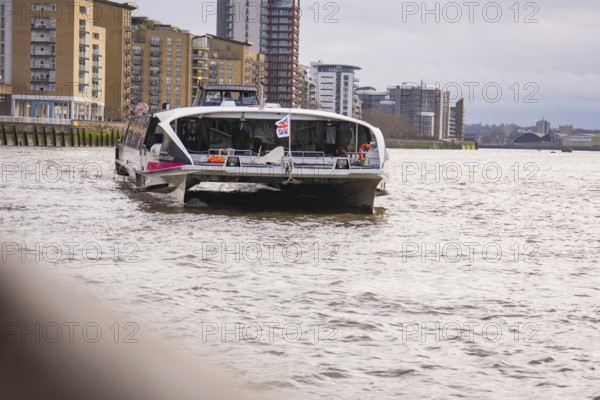A river with tall modern buildings on its banks, with a ship in the foreground, London, England,