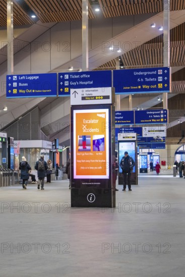 Lively train station with signs and people, modern decor and displays, London, England, Great
