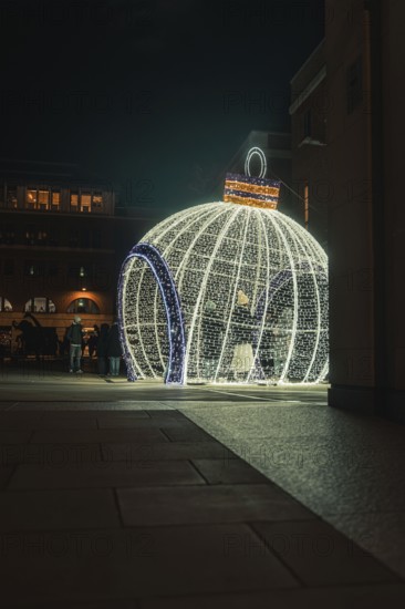 Large glowing Christmas ball on square with people in the evening setting, London, England, Great