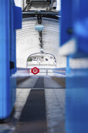 A modern, symmetrical corridor with blue elements leads outside, across boat, London, England,