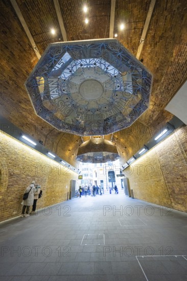 An artistically designed brick vault with lettering and people in an urban space, London Bridge