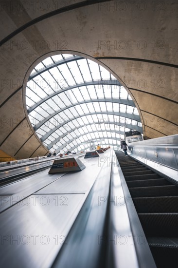 Modern escalator in a futuristic building with arched glass roof and concrete walls, Canary Wharf