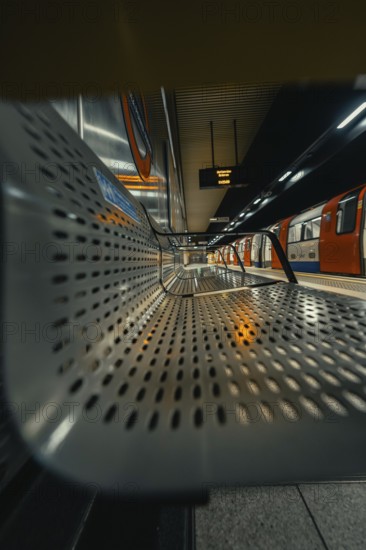 Seating area in a quiet subway station with a modern and metallic architecture, London, United