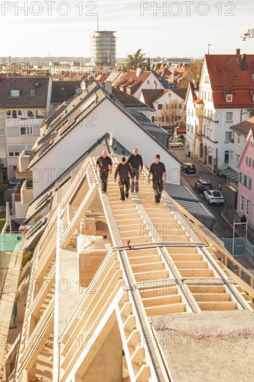 Craftsmen walking on a roof of a new building in an urban environment, carpentry, renovation, roof