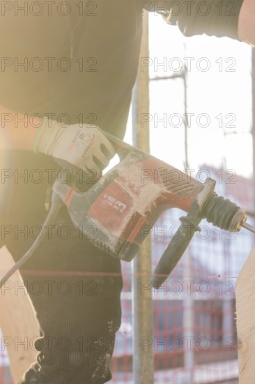 Craftsman with drill during construction work in backlight, carpentry, renovation, roof