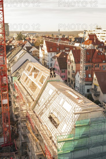 View of an active construction site with cranes, building scaffolding and long scaffolding along a