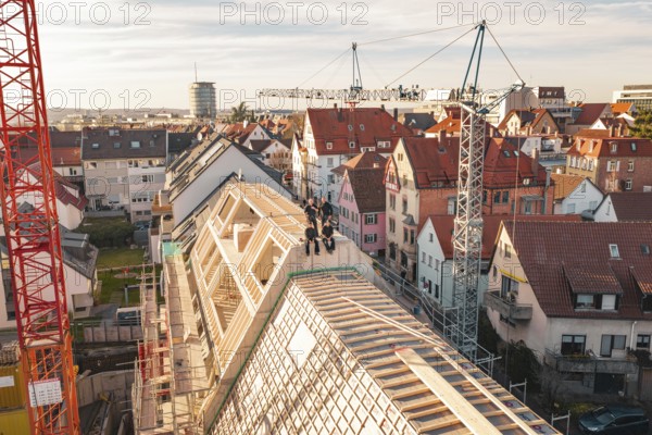 Workers on a half-finished roof surrounded by varied urban development, carpentry, renovation, roof