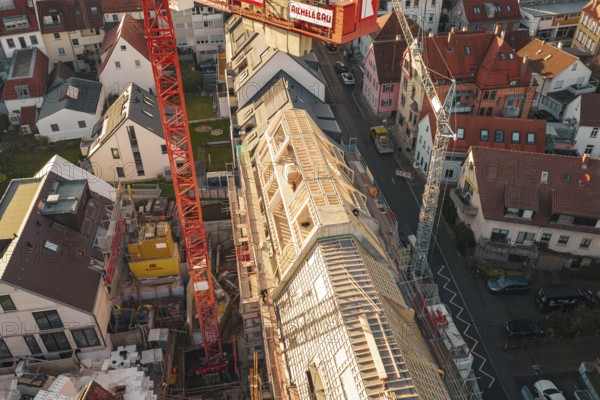 Upper perspective of a construction site in a residential area with visible roof structures,