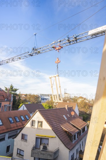 Wood element hanging from a crane over a roof with a clear sky, carpentry, renovation, roof