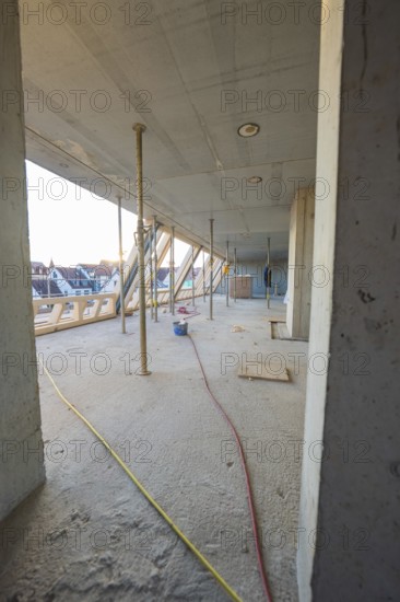 Open interior with construction work, exposed concrete walls and supports, carpentry construction