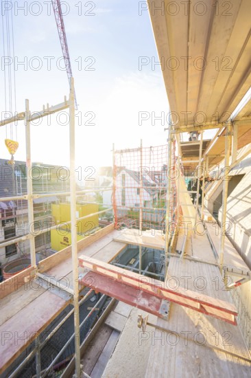 View from above of a construction site with scaffolding at sunset. Urban environment visible,