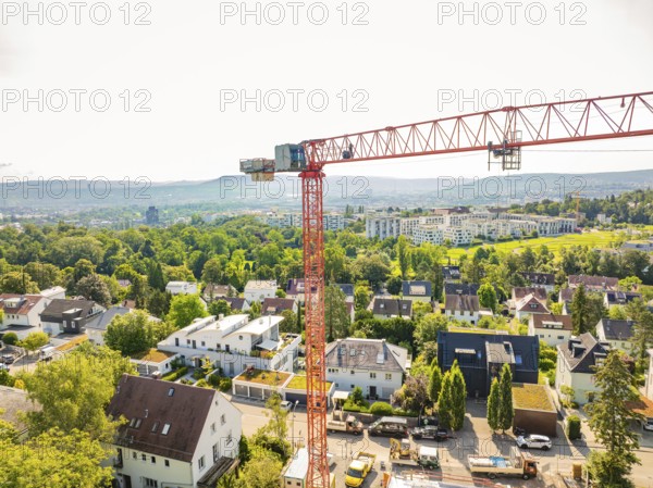 Crane over an urban residential area with green areas and a wide view, construction site of a