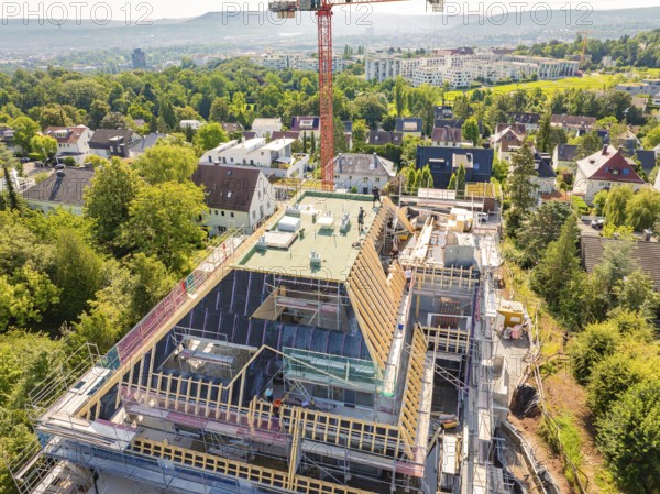 A new building with a construction crane in a residential area, surrounded by green vegetation and