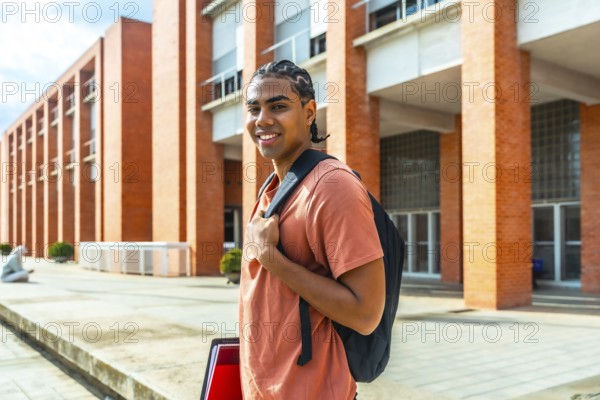 Young hispanic man student standing outdoors at university campus, wearing a backpack and holding