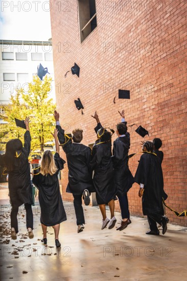 Diverse group of university students celebrating an achievement and success by throwing graduation
