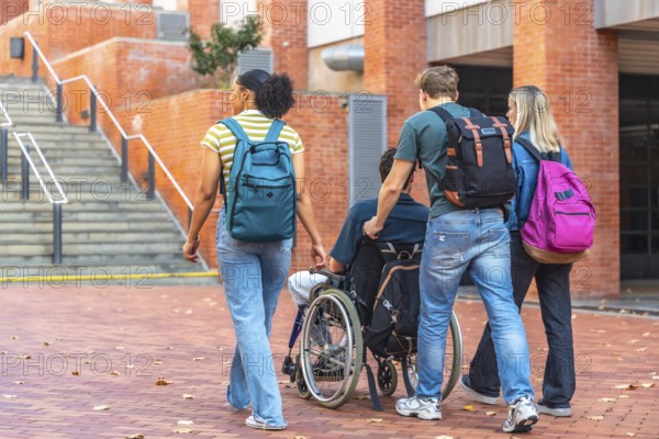 Group of diverse university students walking together on campus, one male student pushing a friend