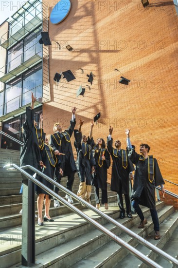 Diverse group of young adult university graduates celebrating a successful academic achievement by