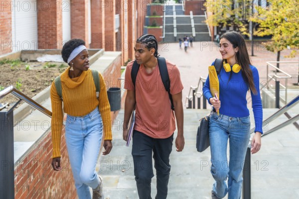 Diverse group of university students walking down outdoor stairs with books and backpacks, chatting