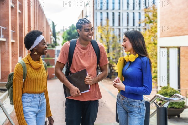 Three diverse students walking together and enjoying a conversation while moving through a modern