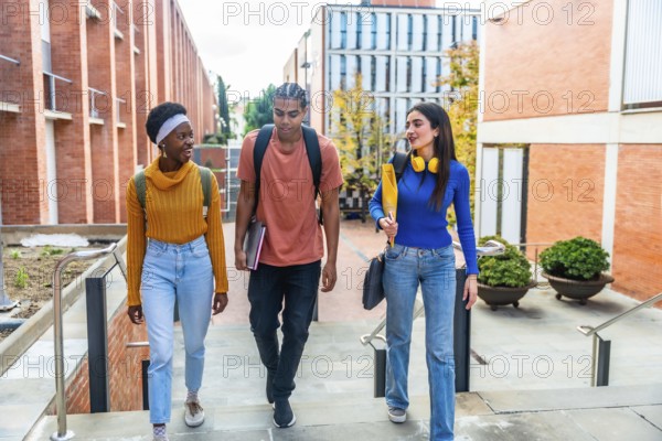 Diverse students walking down university campus stairs during a sunny day, carrying backpacks and
