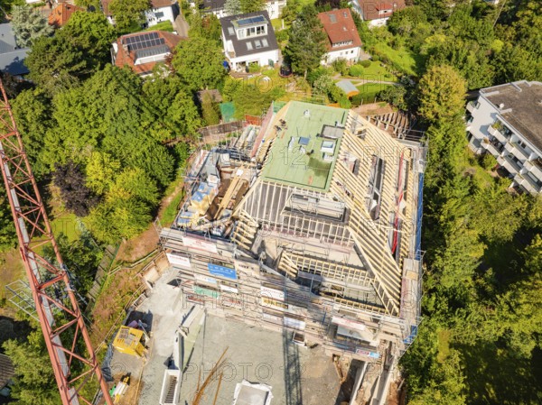 Roof of a house under construction with crane and surrounding houses in the countryside,