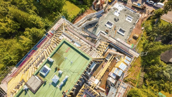 Aerial view of a construction site with roof structures and materials in a green environment,